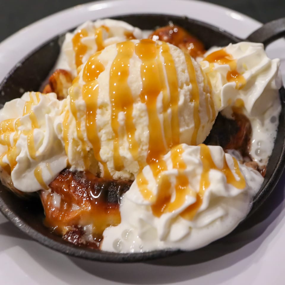 Skillet dessert with vanilla ice cream, whipped cream, and caramel drizzle.