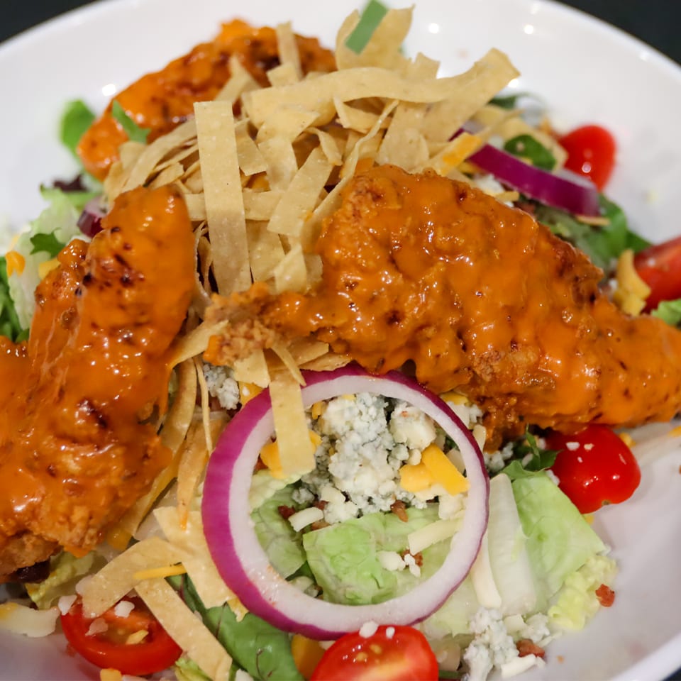 Buffalo chicken salad with tortilla strips, red onion, blue cheese, and cherry tomatoes.